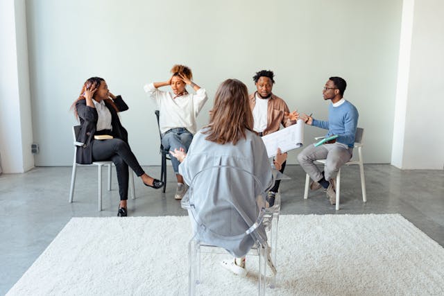 Photo by Antoni Shkraba Studio Therapist facing away from camera as group members face her and camera. They appear to be talking to each other.
